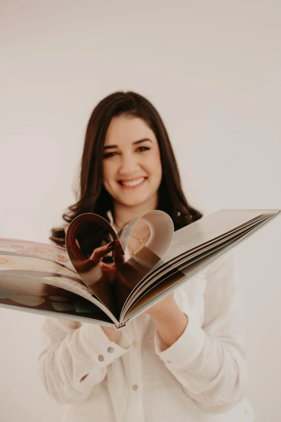 Thais segurando um livro ilustrado em seu retrato profissional